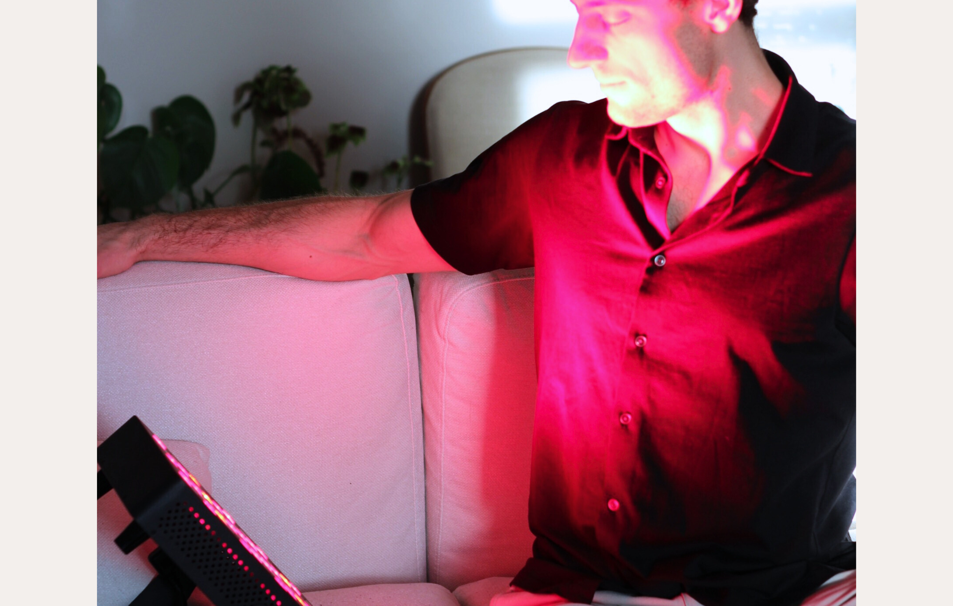 Person sitting on a couch engaged in a red light therapy session.